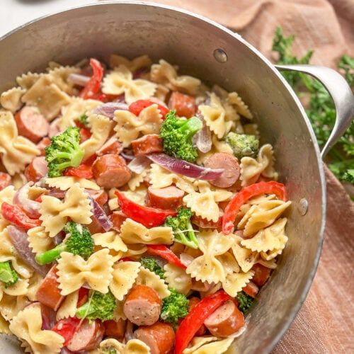 a pan filled with pasta and vegetables on top of a wooden table