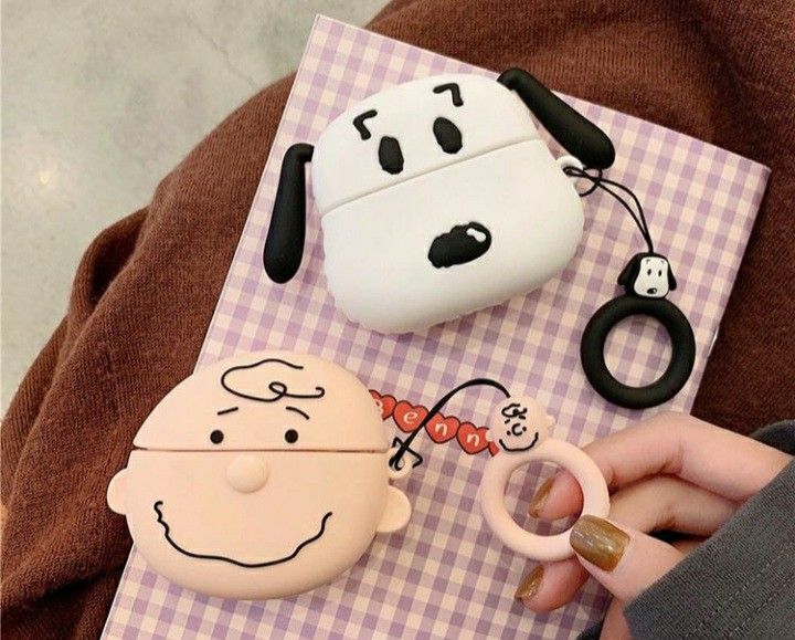 a person is holding an airpods case in front of some other items on a table