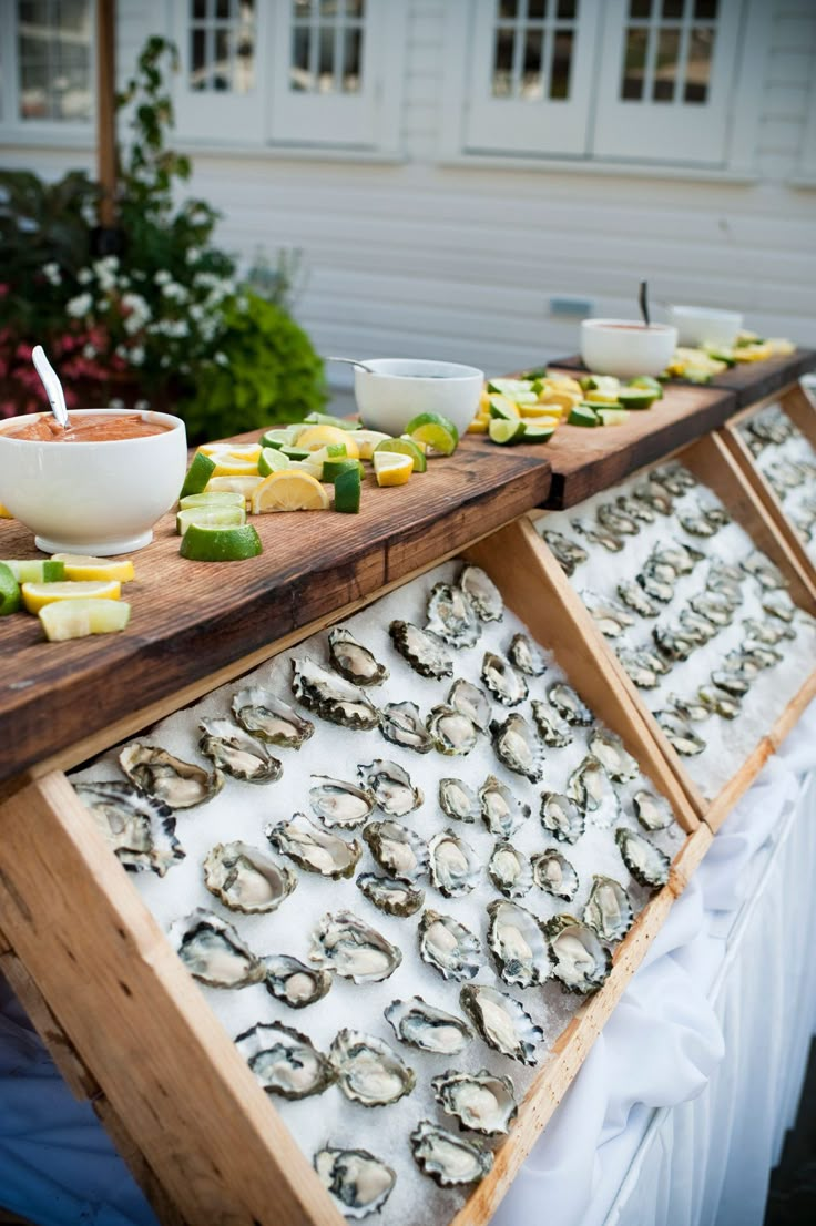 an assortment of food is displayed on a long wooden table with white cloths and bowls