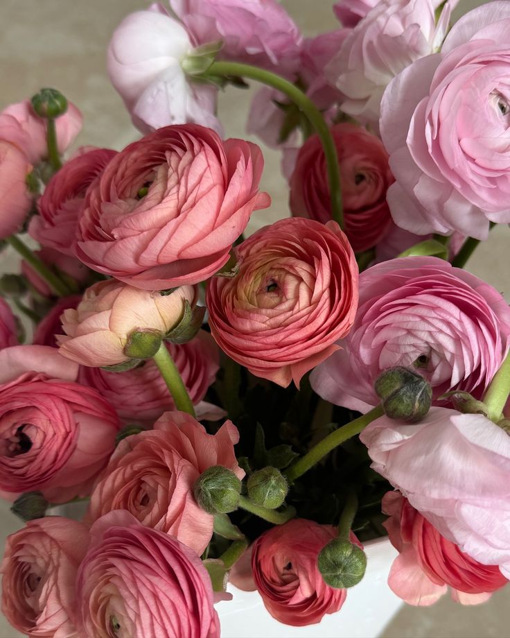 a white vase filled with pink and red flowers