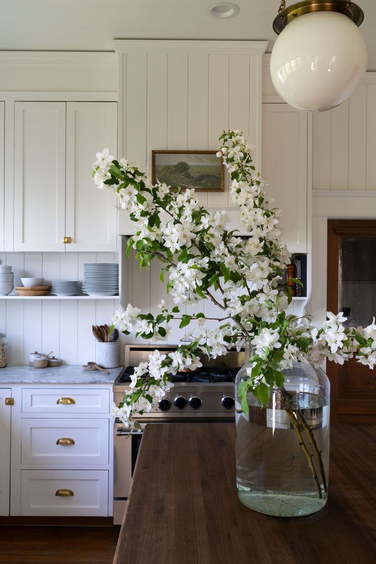 a vase filled with white flowers sitting on top of a wooden kitchen counter next to an oven