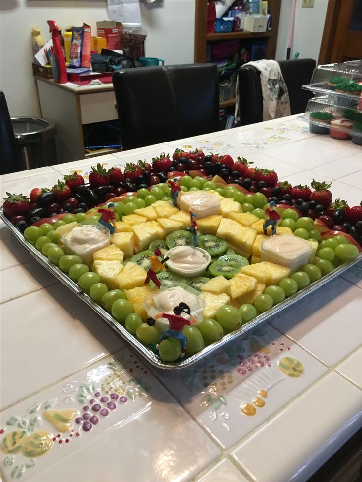 a platter filled with fruit and cheese on top of a kitchen counter