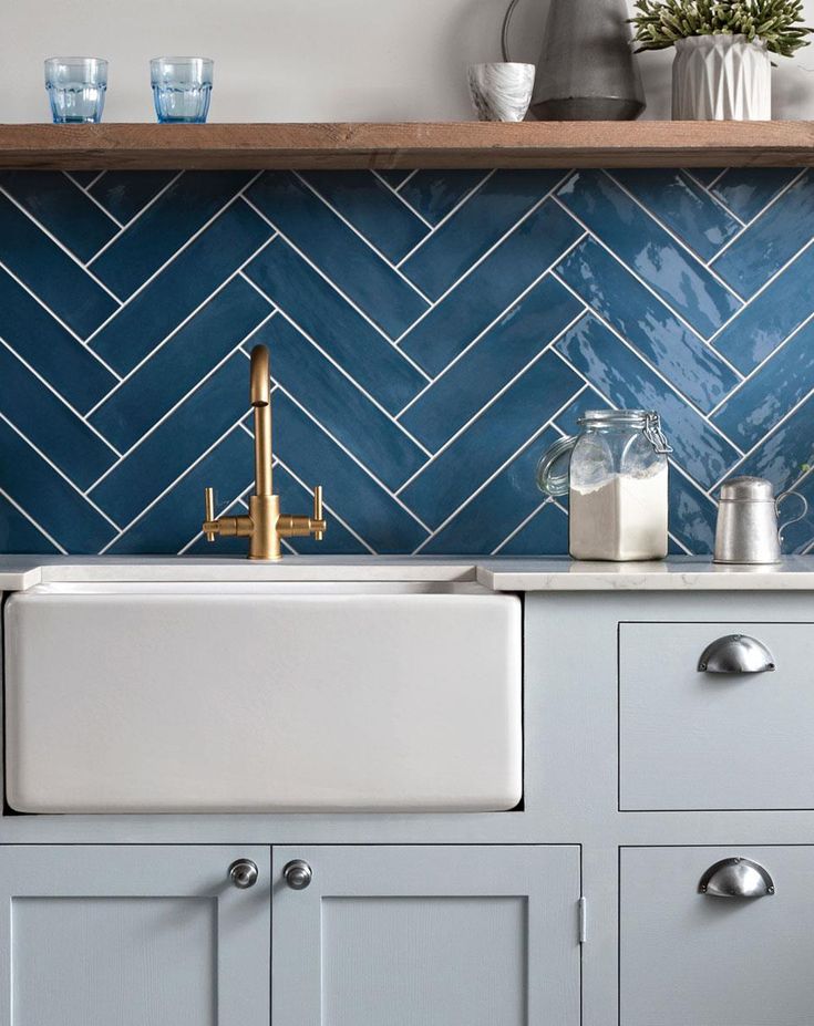 a kitchen with blue and white tiles on the backsplash, gold faucet