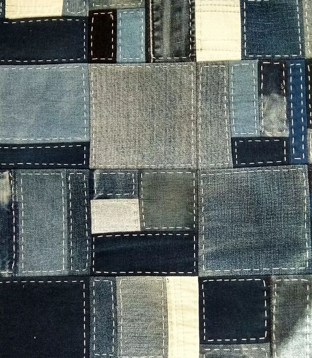 an old patchwork denim fabric with white stitching