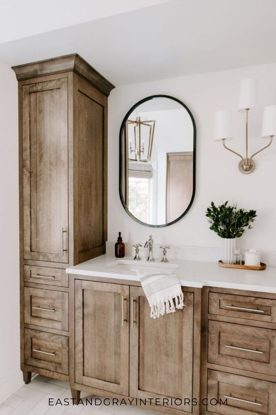 a bathroom with wooden cabinets and a round mirror