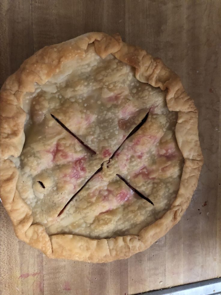 an uncooked pie sitting on top of a wooden table next to a knife