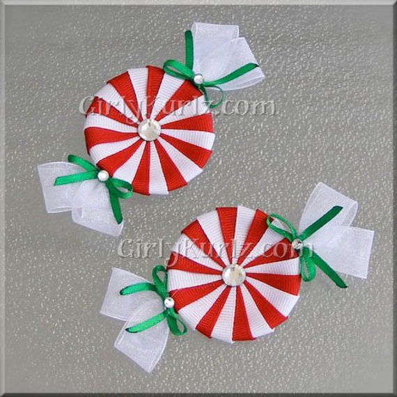 two red and white candy lollipops with green bows on them sitting on a table