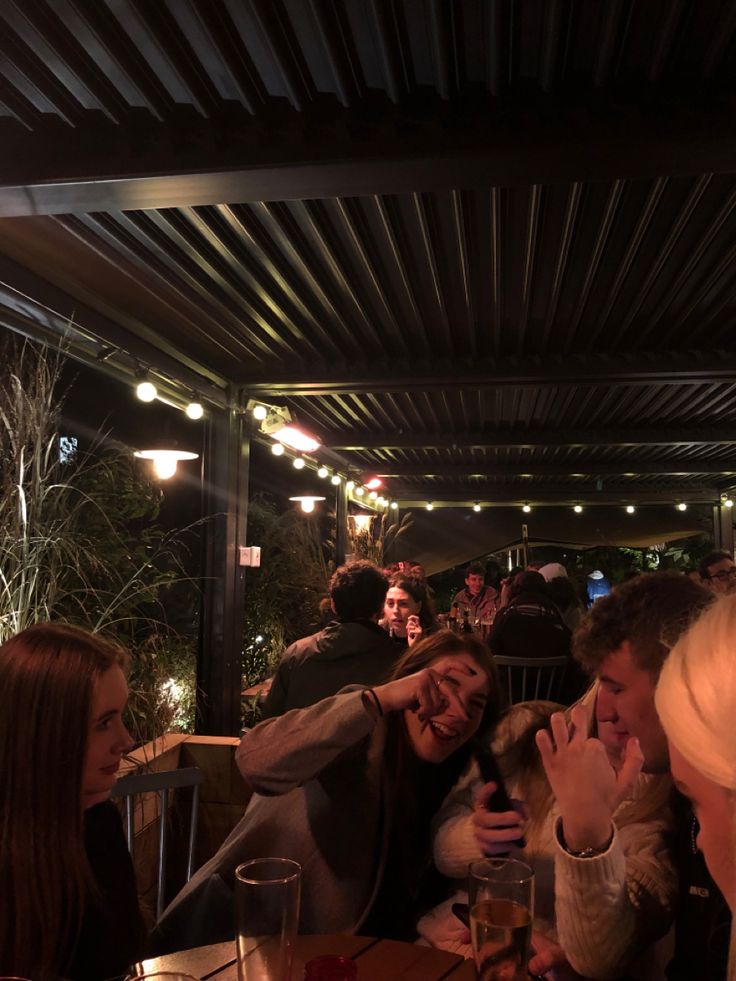 a group of people sitting at a table with food and drinks in front of them