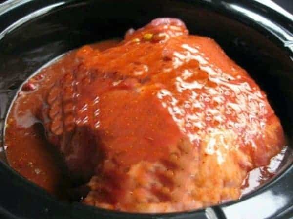 a slow cooker filled with meat covered in sauce