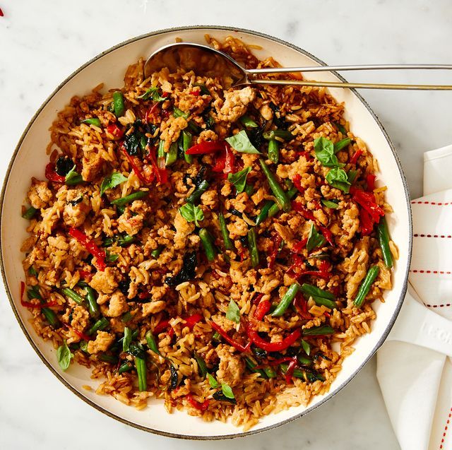 a bowl filled with rice and vegetables on top of a white tablecloth next to a fork