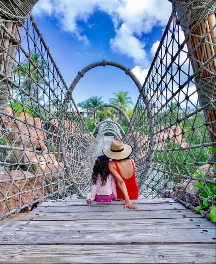 a woman sitting on top of a wooden bridge