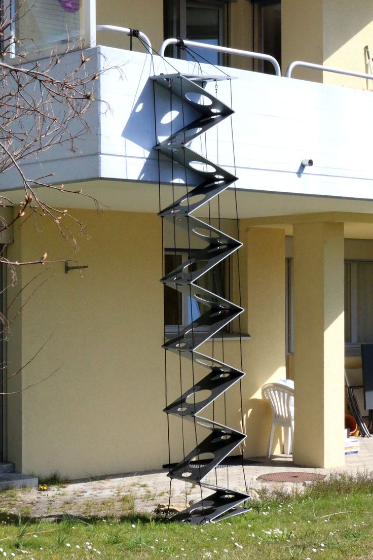 there is a metal spiral staircase going up the side of a building in front of a white chair