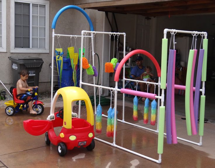 a child's toy car is parked in front of an outdoor play area with toys