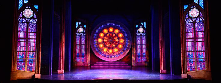 an empty stage with stained glass windows in the background and a large circular window behind it