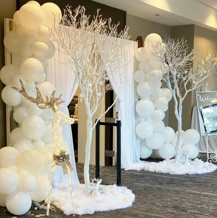 white balloons and trees are set up in front of the entrance to a reception room