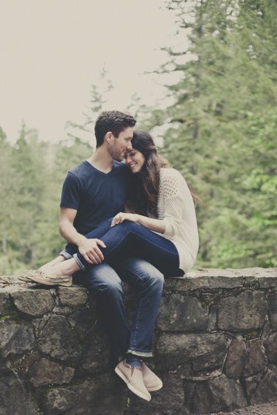 a man and woman are sitting on a stone wall