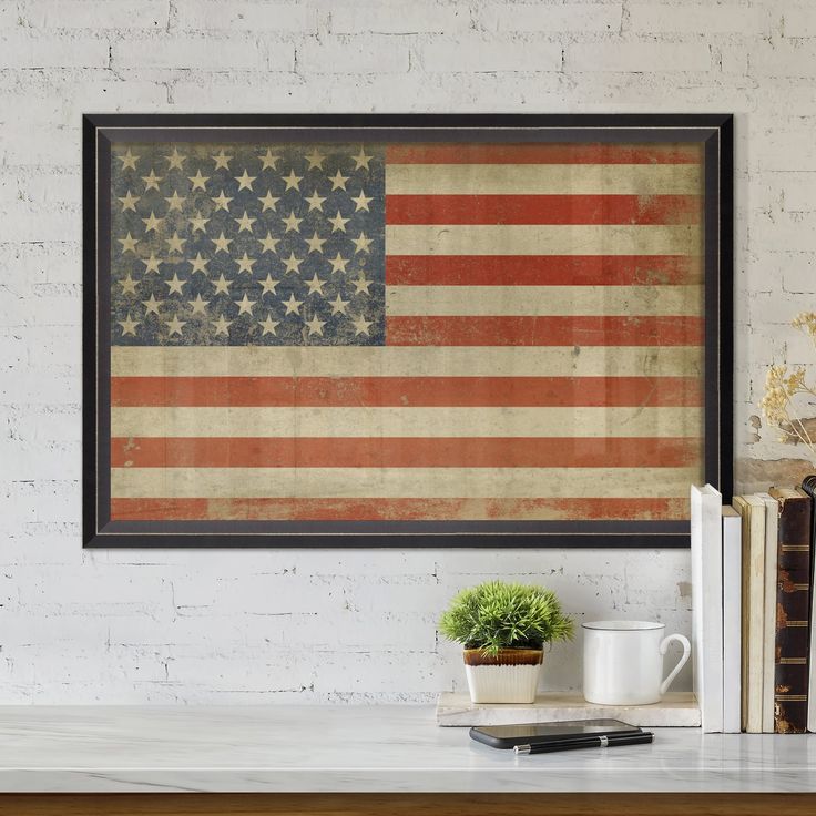 an american flag is hanging on the wall above a table with books and a coffee mug