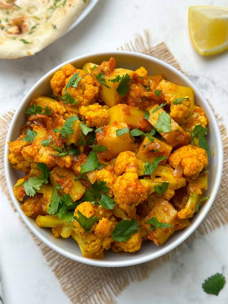 a white bowl filled with cauliflower and garnished with cilantro