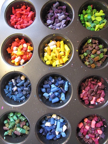 a muffin tin filled with lots of different colored crayons in each cup