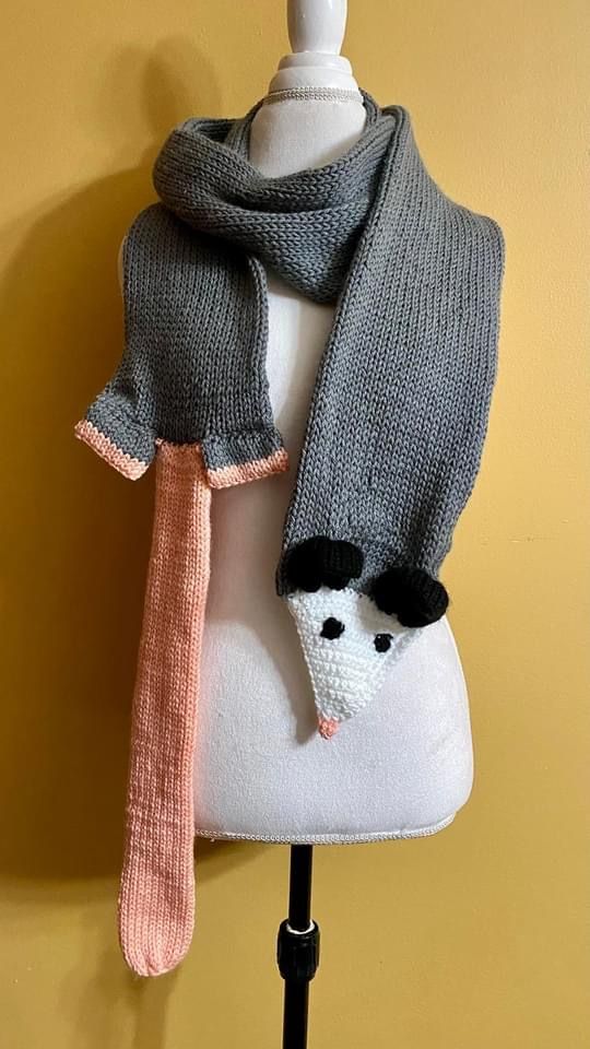 a white mannequin wearing a gray sweater and scarf with a cat on it