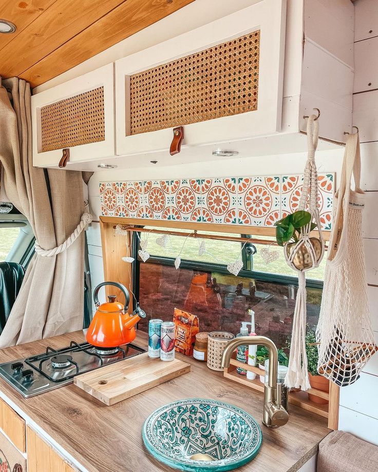 a kitchen area with a sink, stove top and window in the back side of a camper