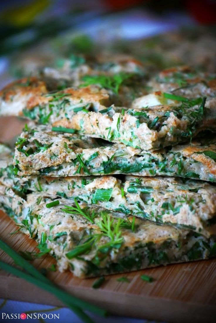 several pieces of food on a wooden board with green herbs and seasoning sprigs