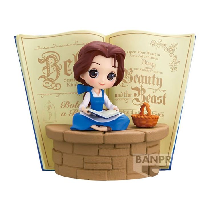 a figurine sitting on top of a brick wall next to an open book