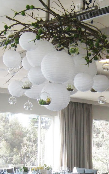 the dining room is decorated with white paper lanterns and greenery hanging from the ceiling