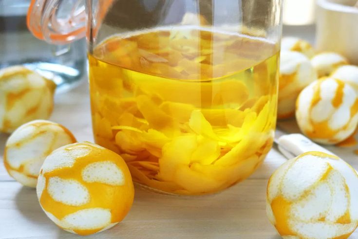 there are some peeled oranges next to a jar with liquid in it on the table