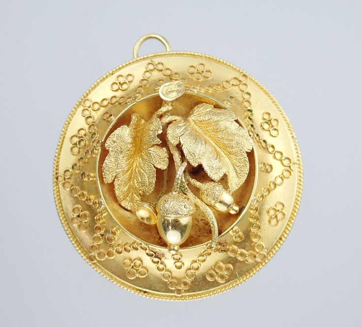 a gold pendant with leaves and pearls on it