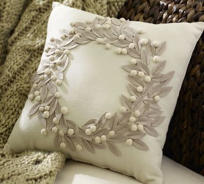 a white pillow sitting on top of a bed next to a brown basket filled with pillows