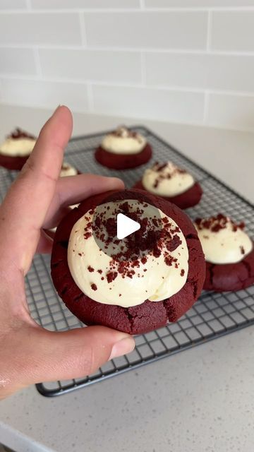 a person holding a chocolate cookie with white frosting