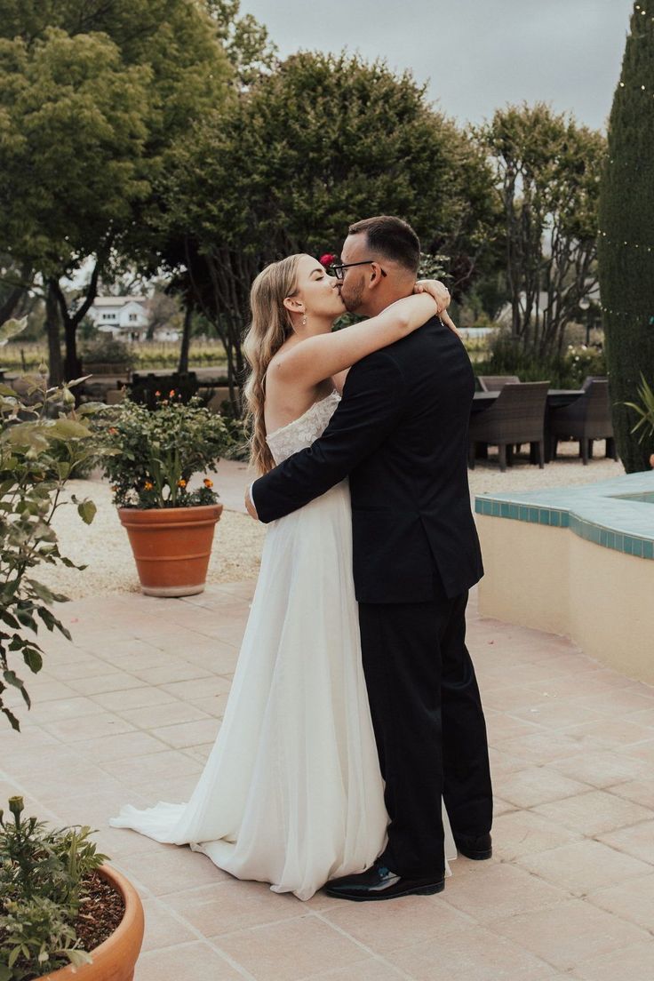 a bride and groom kissing in front of a pool