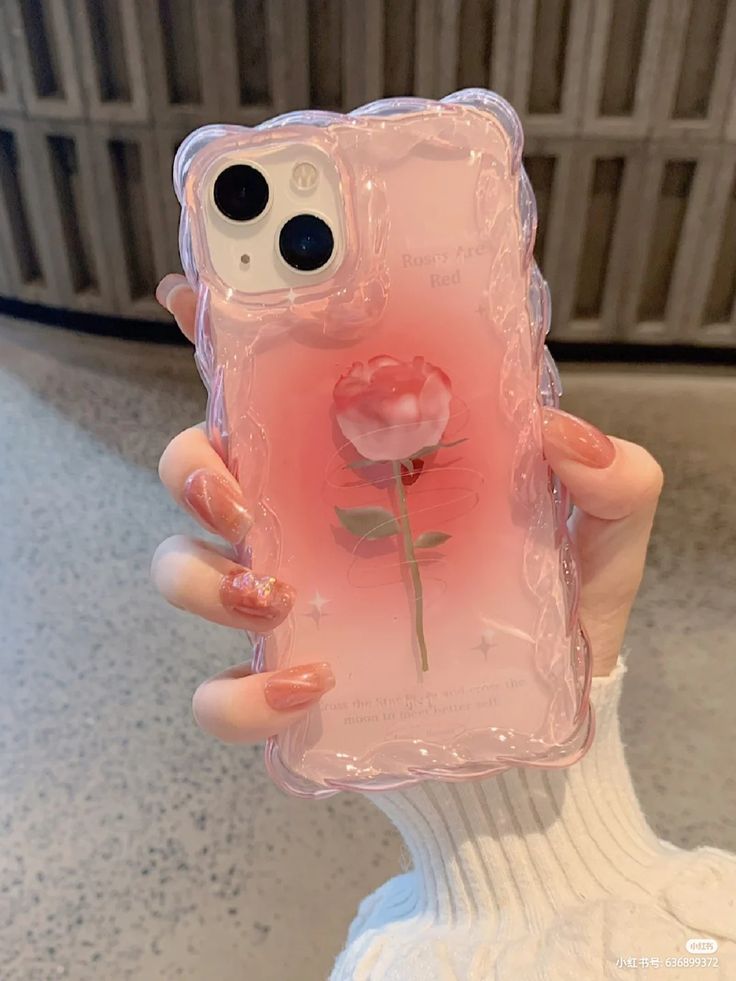 a person holding up a pink phone case with a flower on the front and bottom