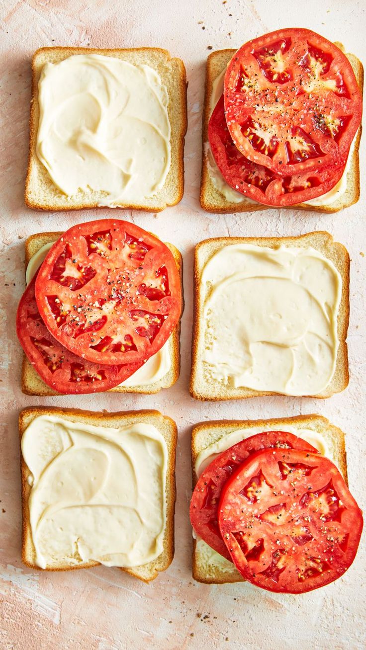 four slices of bread with cream cheese and tomatoes on them