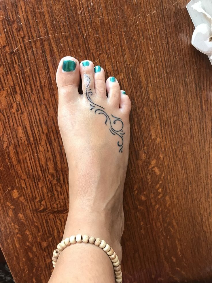 a woman's foot with blue and white nail polish on it next to a wooden table