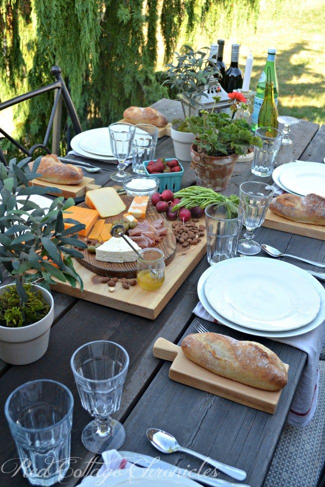 an outdoor table with plates and glasses on it