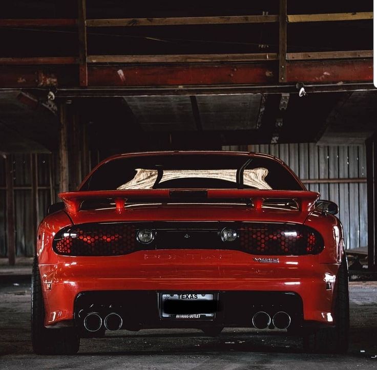 the rear end of a red sports car parked in a garage