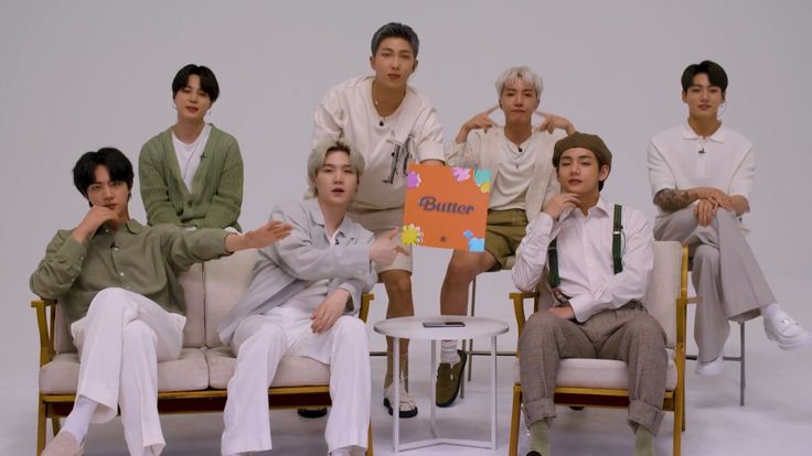 a group of young men sitting on top of a white couch next to each other