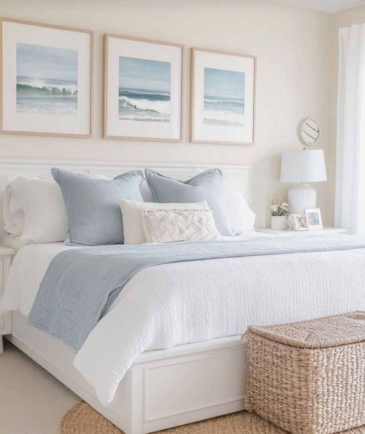 a bedroom with white and blue bedding, pictures on the wall above the bed