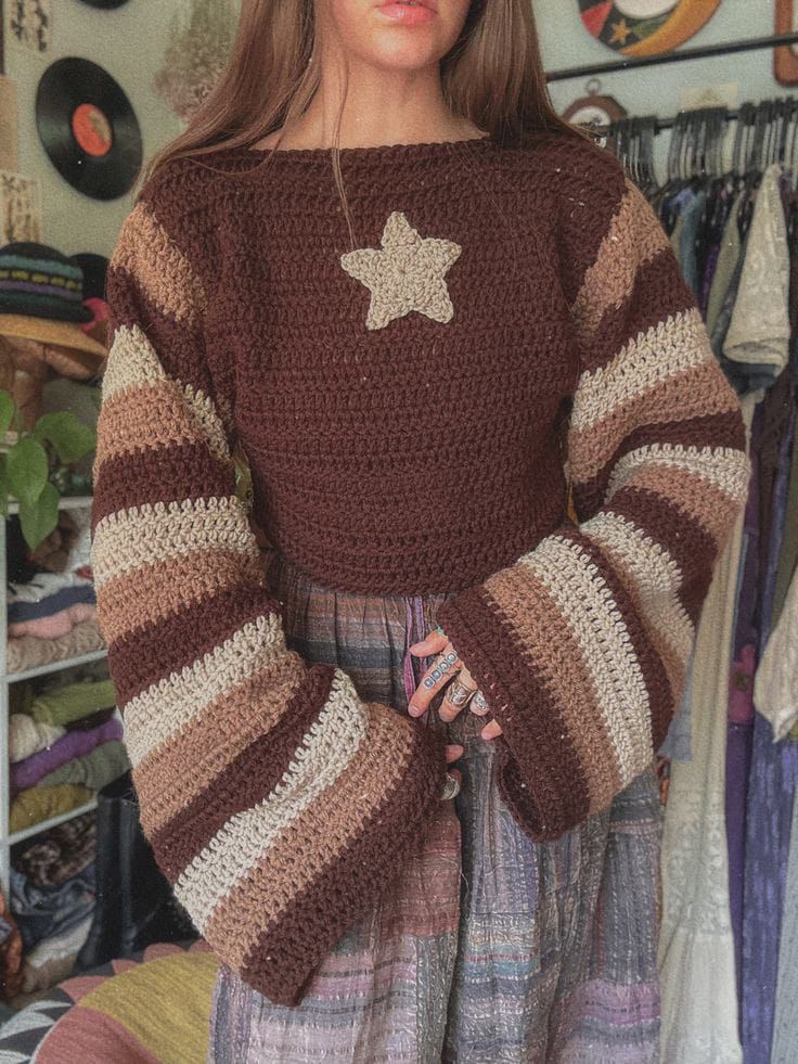 a woman wearing a brown and white sweater standing in front of a rack with clothes on it