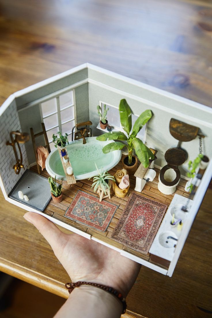 a person holding up a doll house with furniture and plants in the room around it