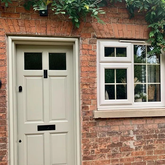 a brick building with two white doors and windows on each side, next to a black cat