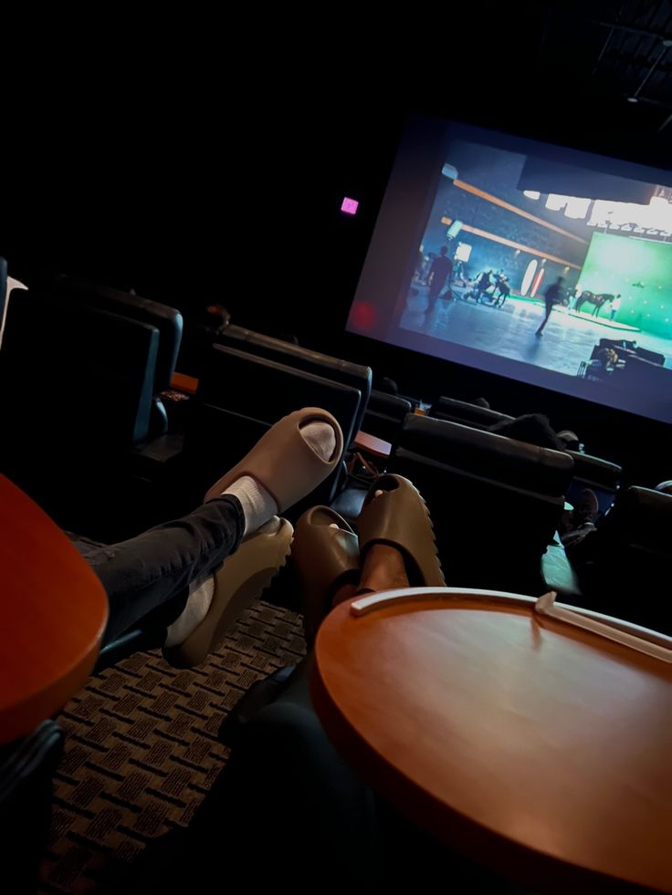 a person laying on the floor in front of a movie screen with their feet up