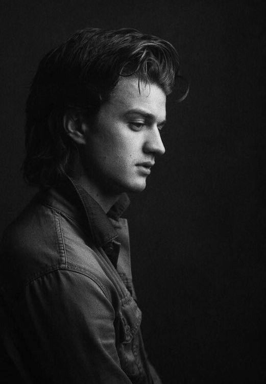 a black and white photo of a man with long hair wearing a denim shirt looking to the side