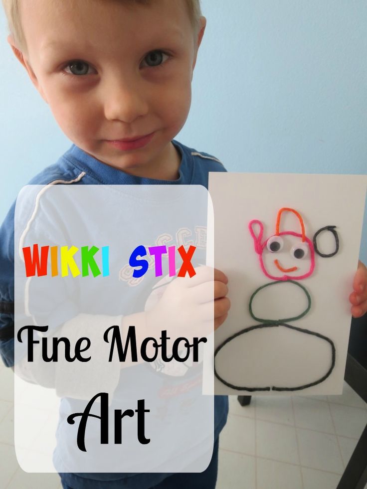 a young boy holding up a paper cutout with the words wiki - stix fine motor art