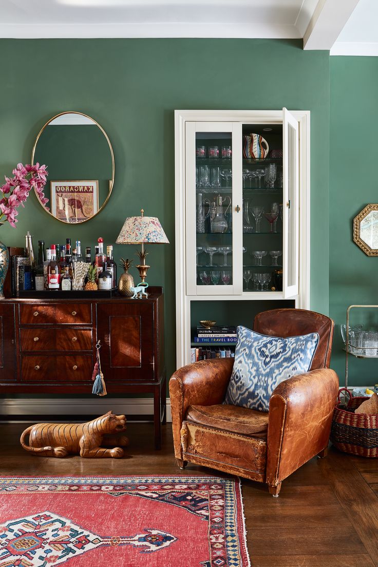 a living room with green walls and wooden furniture in the corner, including a brown leather chair