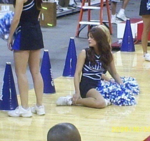 a cheerleader sitting on the floor with her pom poms in front of her