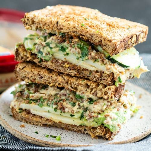 three sandwiches stacked on top of each other with cheese and meat in the middle, sitting on a plate