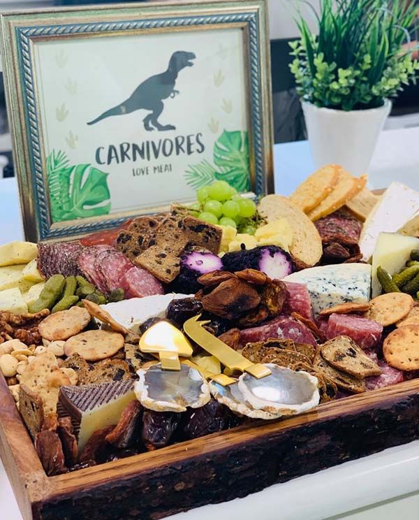 a wooden tray filled with different types of cheese and crackers on top of a table